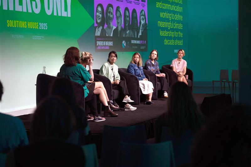 Six women on chairs facing a crowd