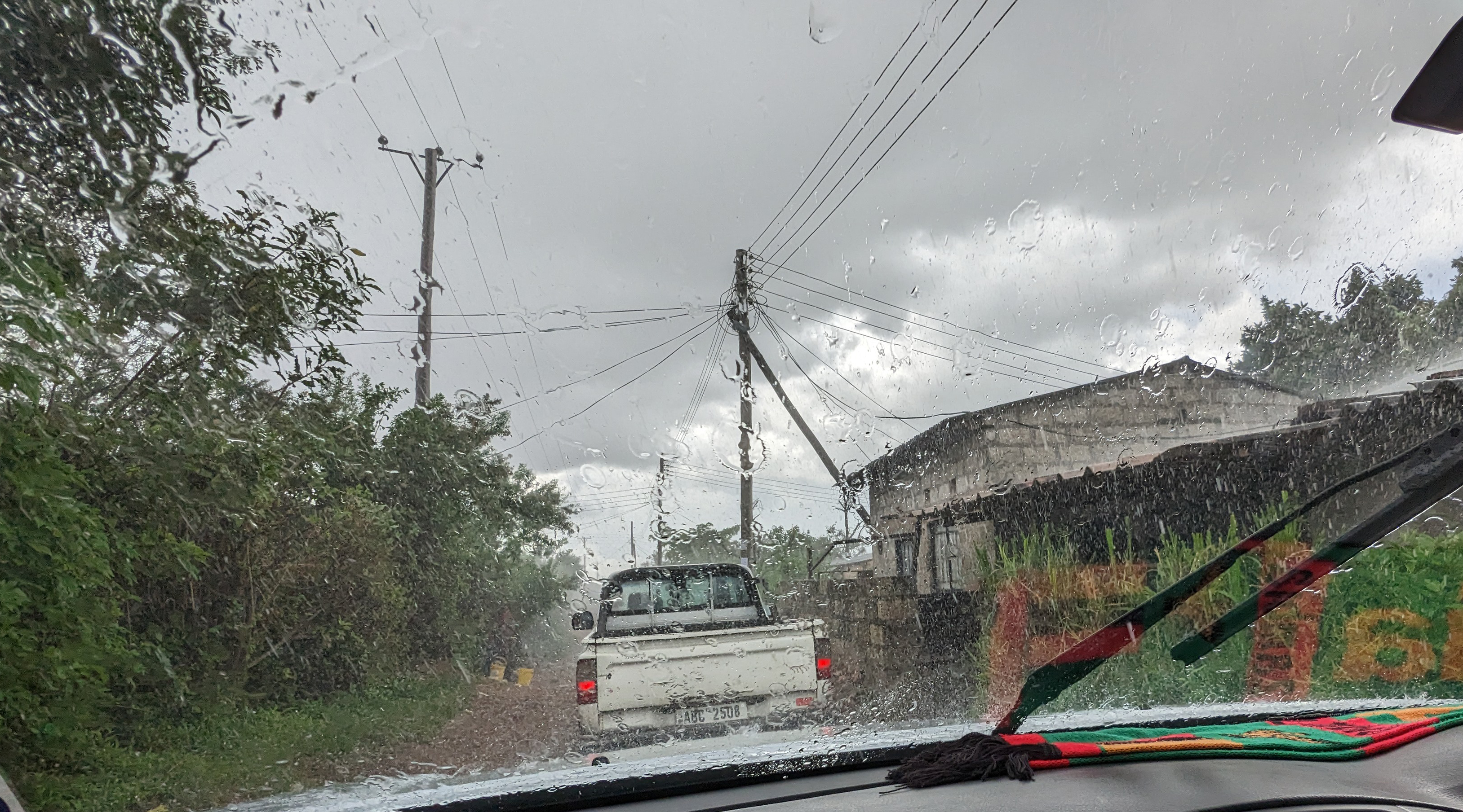 Image of small village in Zambia with derelict buildings and a car in the rain.