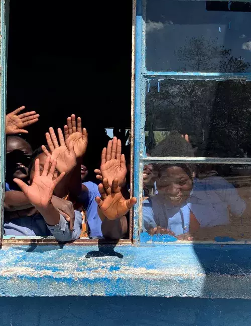 School children waving through an open window in Zambia
