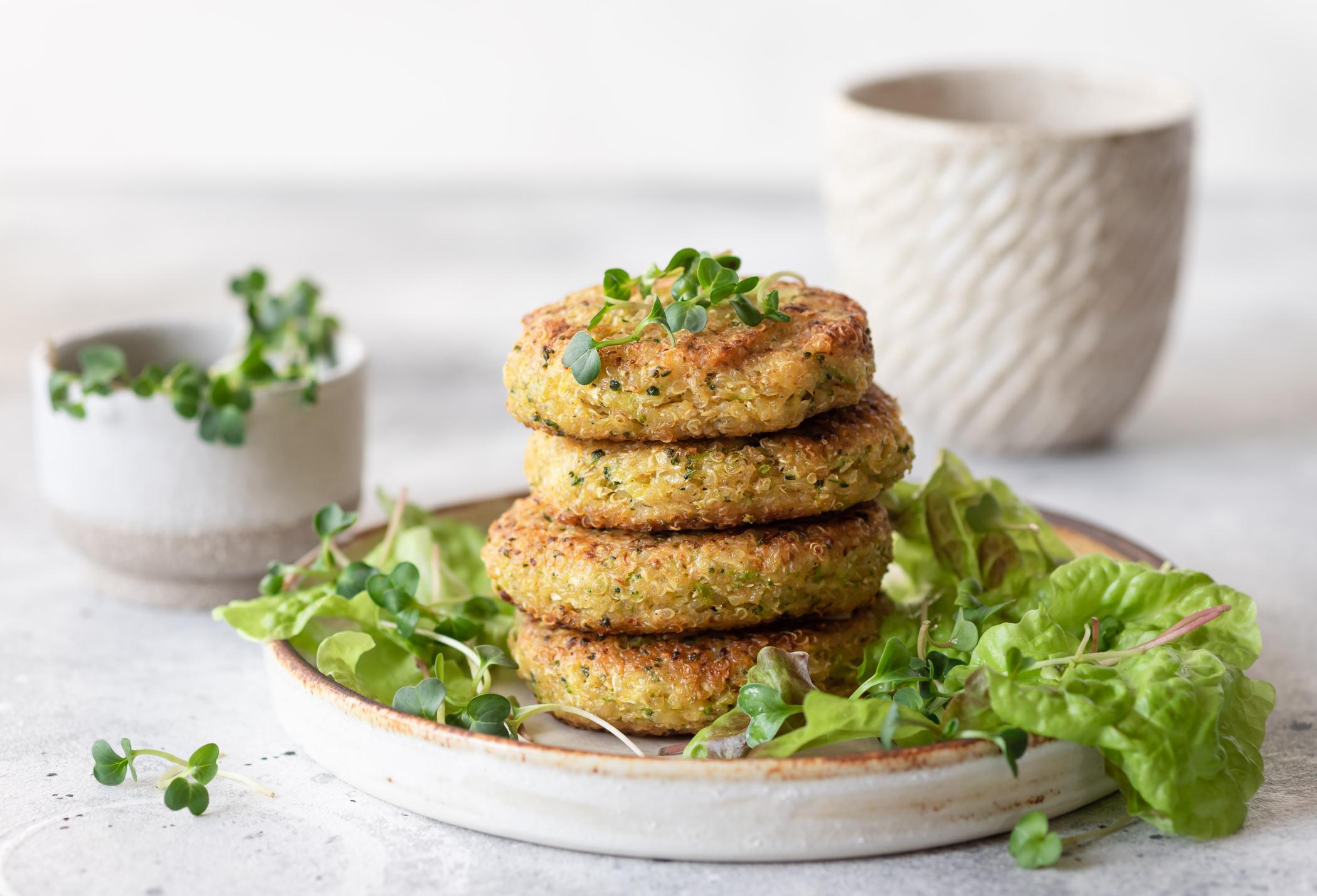 Green broccoli and quinoa burgers served with lettuce and microgreens.