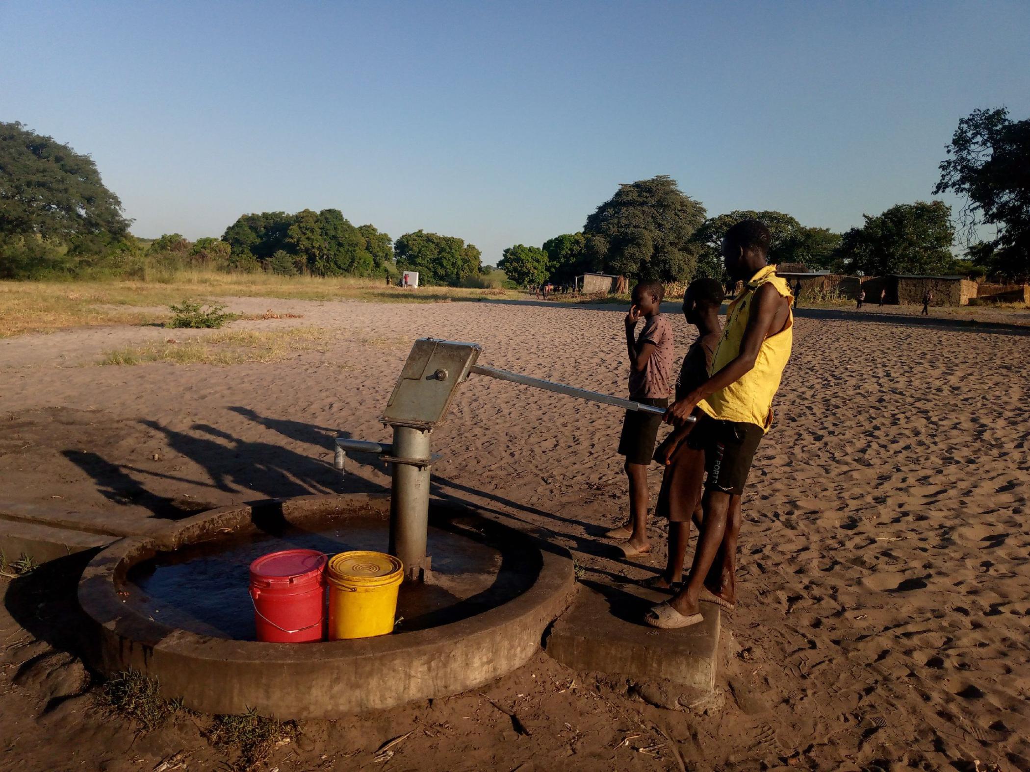 Two people stand by water pump 